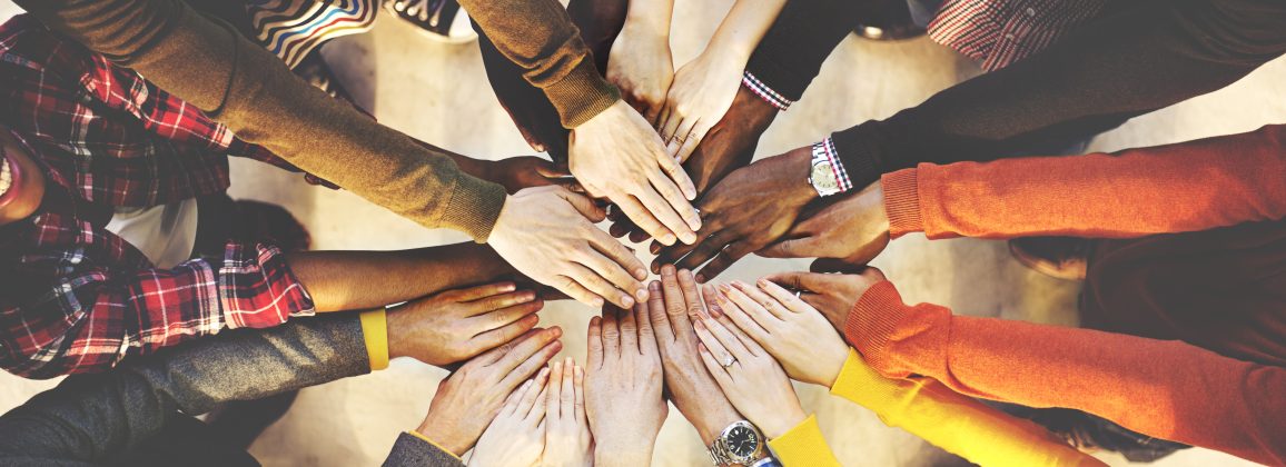 Banner image of multiple individuals putting their hands in a circle for a "Go Team" moment